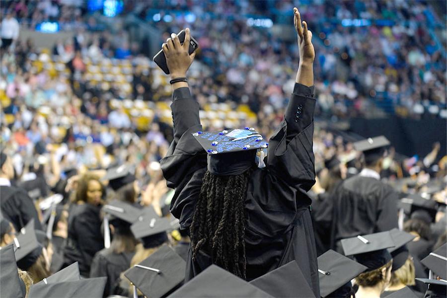 学生在毕业典礼上举着毕业帽.